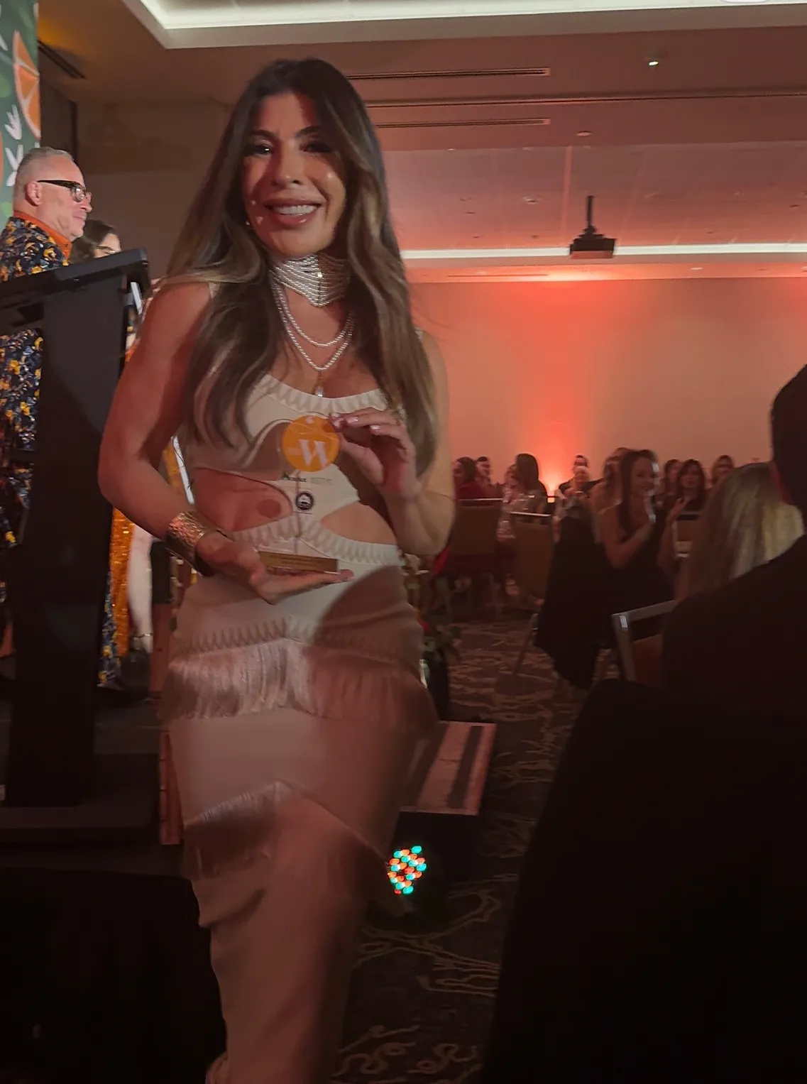 Woman in a beige cut-out dress at an evening awards event